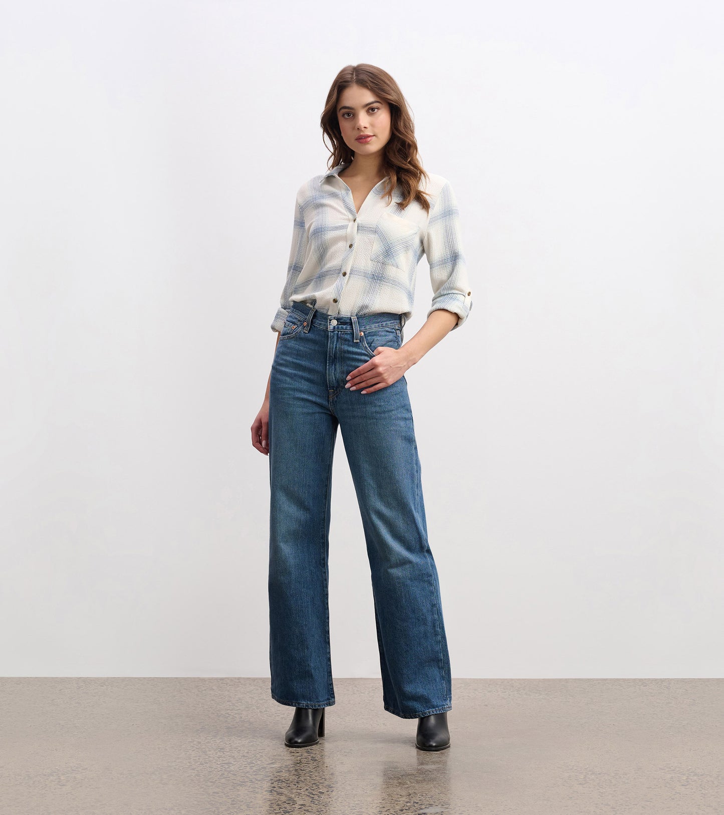 Turquoise plaid button-down shirt with a collar, rolled sleeves, paired with high-waisted jeans and black boots.