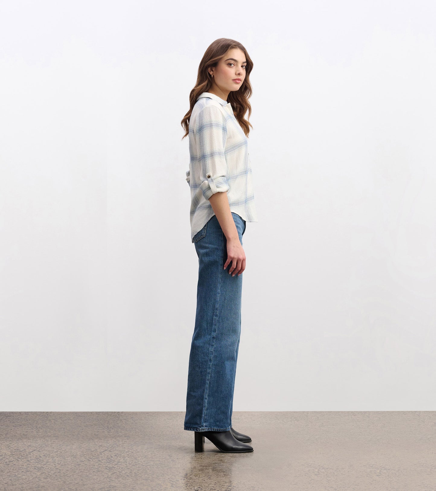 Turquoise plaid button-down shirt with rolled sleeves, styled with high-waisted jeans and heeled boots, shown from the side.