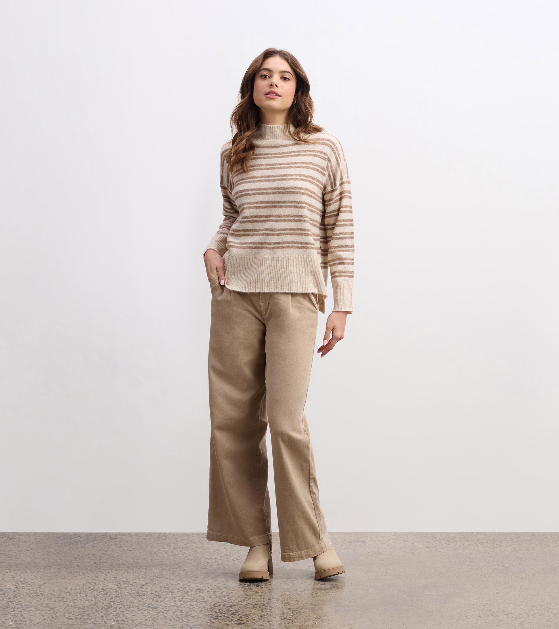 Mock neck sweater in camel with double stripes, paired with beige wide-leg pants, styled for a casual look.
