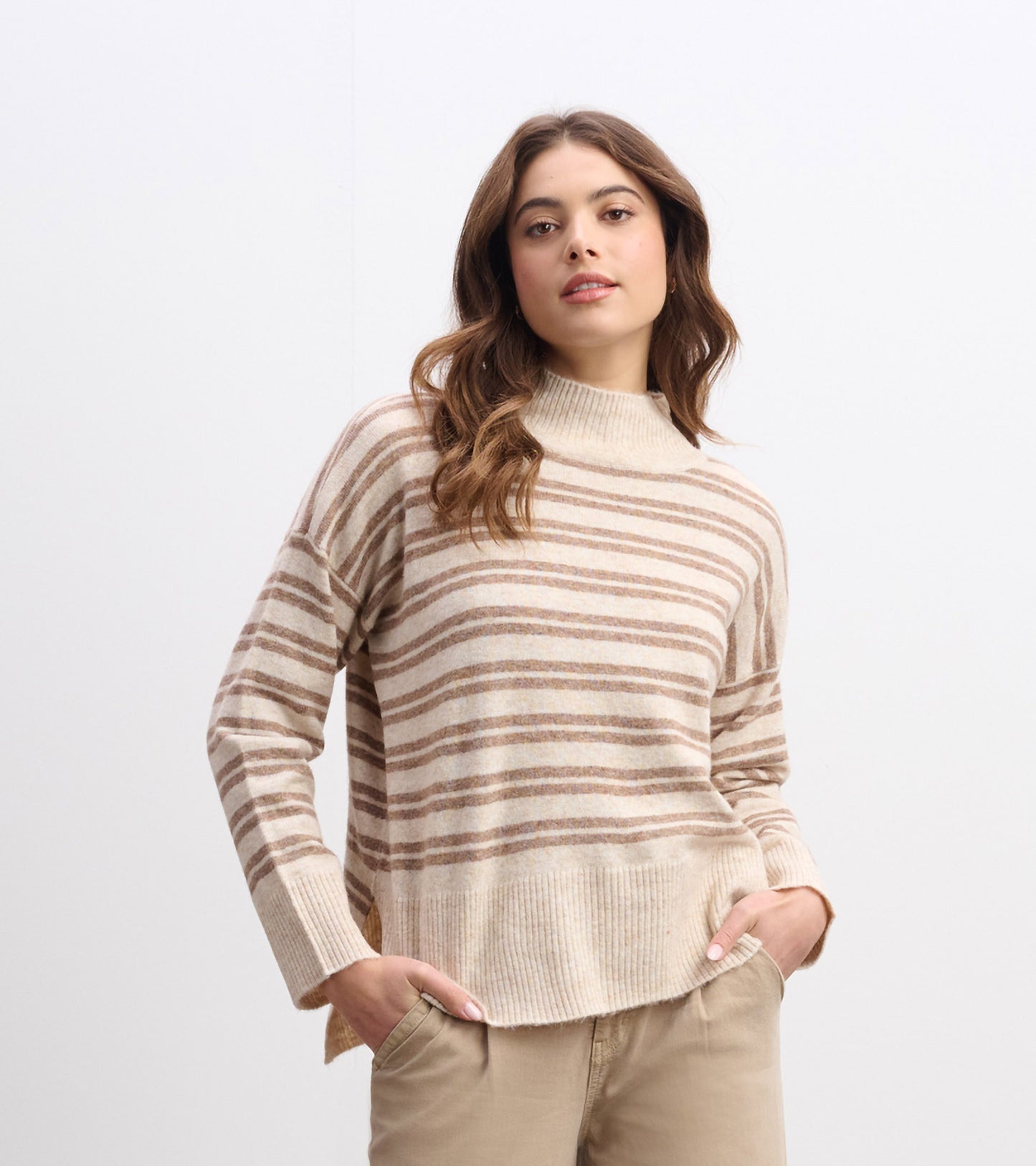 Cream and camel striped mock neck sweater with long sleeves and ribbed hem, worn with beige pants.