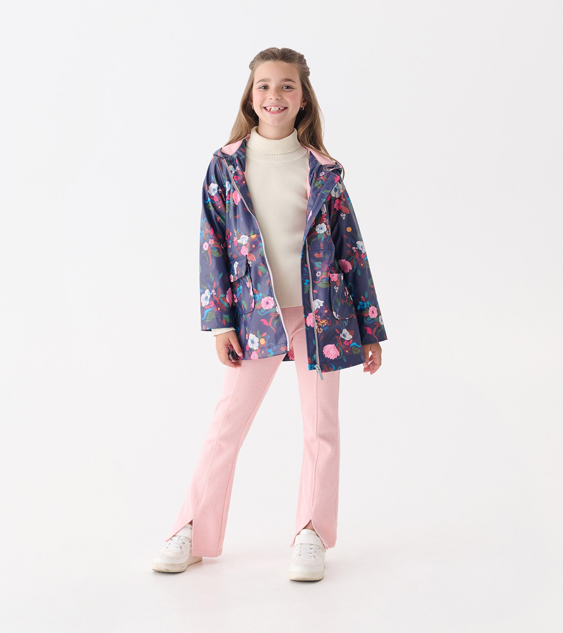Floral zip-up rain jacket in navy with pink accents, featuring a hood and pockets, worn over a light sweater and pink pants.