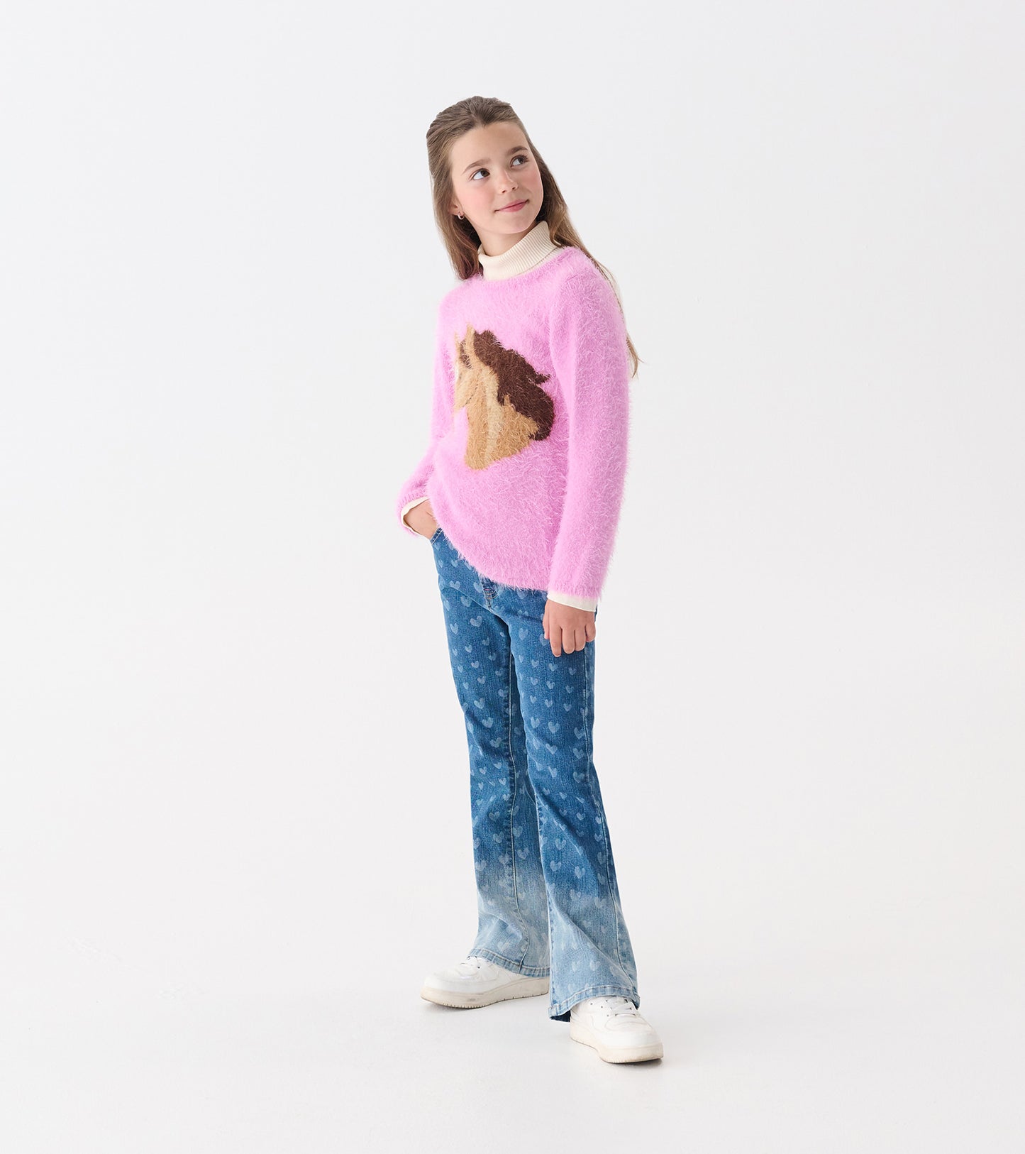 Pink fluffy sweater featuring a horse design, paired with blue patterned jeans and white sneakers.
