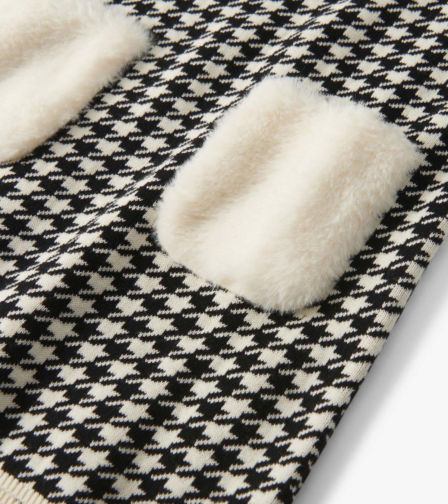 Black-and-white houndstooth sweater dress with cream faux fur pockets, close-up detail view