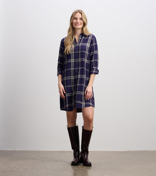 Navy plaid shirt dress with button front, long sleeves rolled up, and a relaxed fit, styled with knee-high boots.