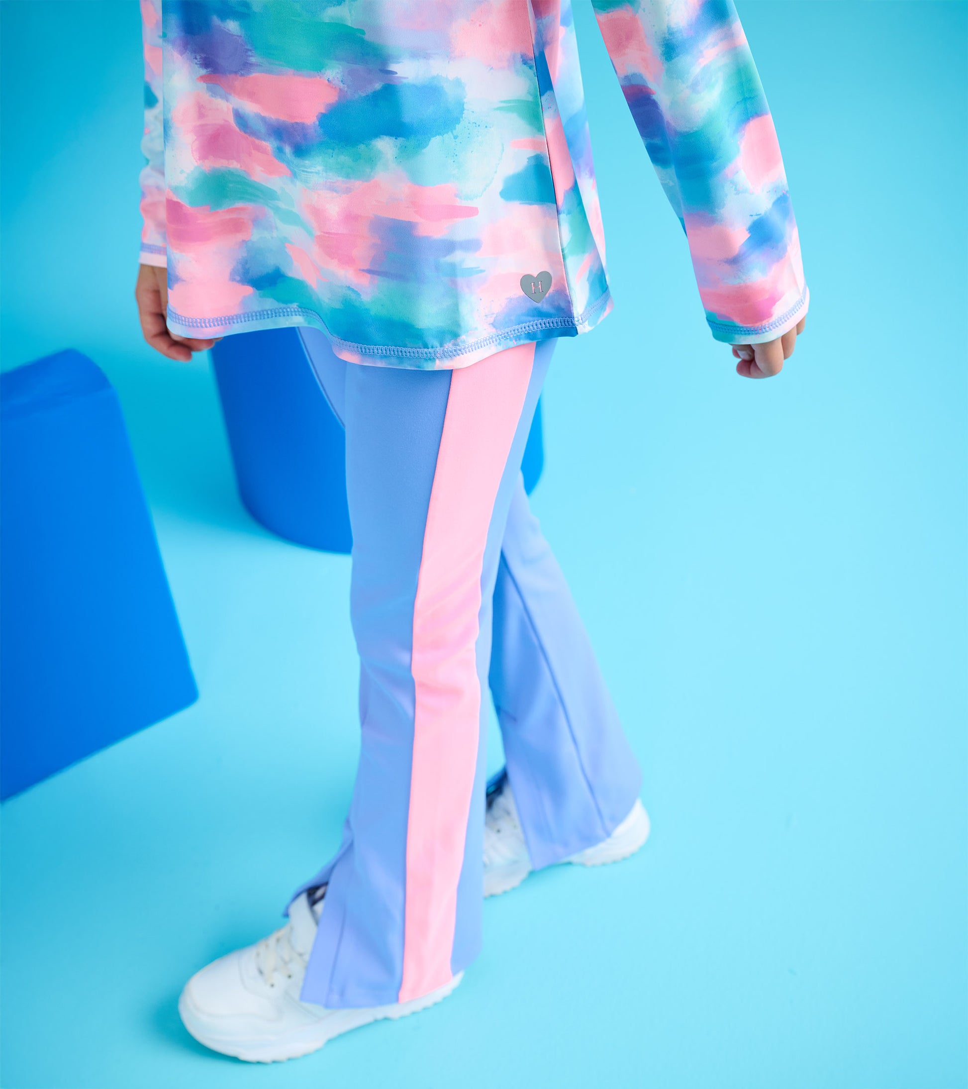 Purple active flared pants with pink side stripes, ideal for active wear, shown on a child with white sneakers.