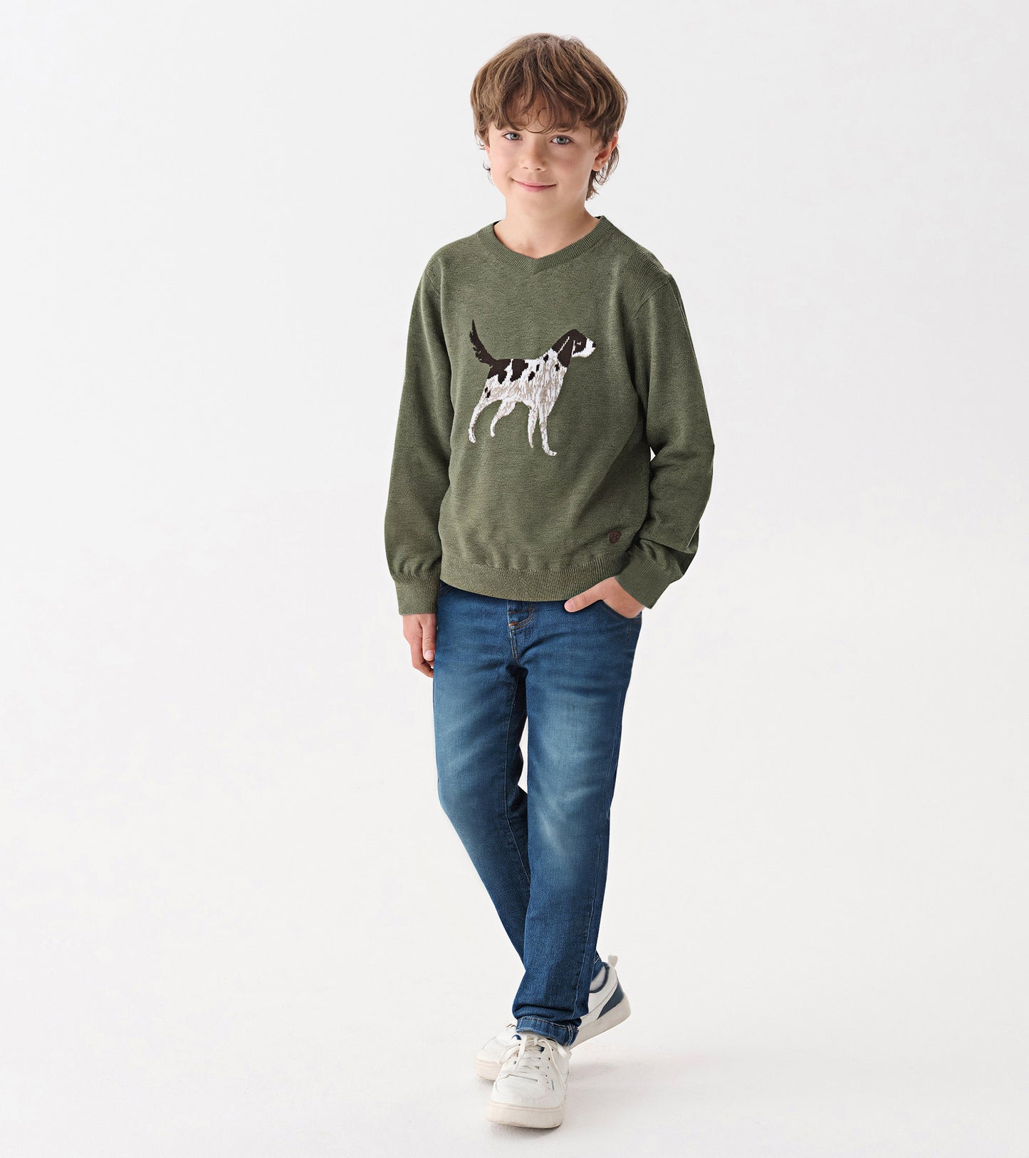 Green V-neck sweater featuring a dog graphic, worn by a boy with blue jeans and sneakers, standing against a white backgroun…