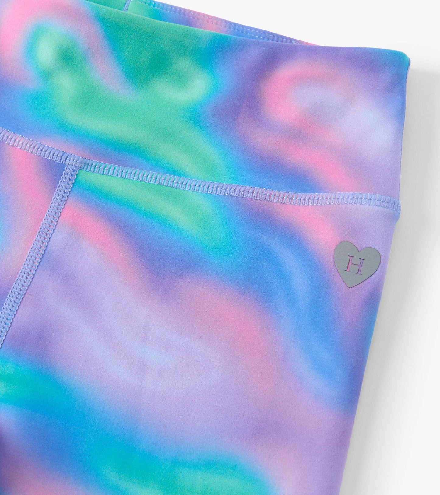 Colorful leggings featuring a swirling pattern of pink, blue, and green with a small heart logo on the waistband.