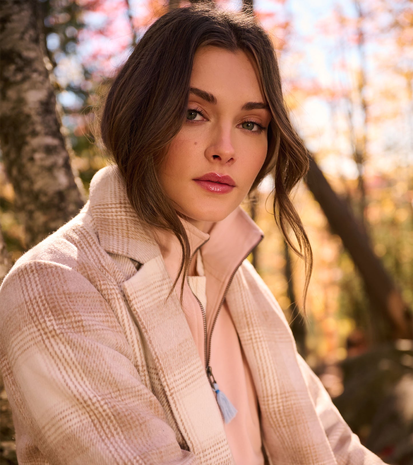 Light taupe plaid jacket with a zip front and high collar, shown on a model outdoors.