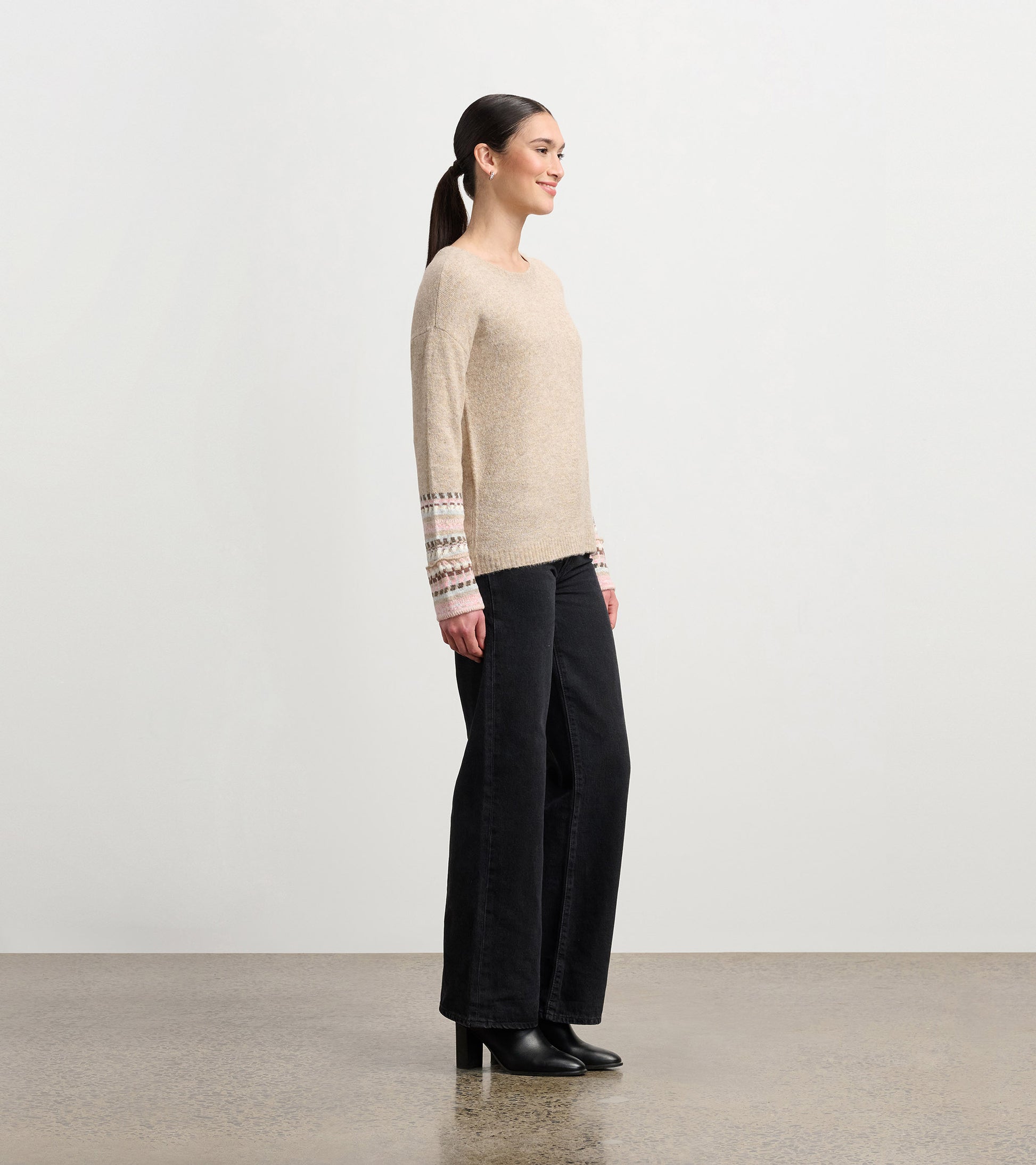 Oatmeal melange sweater with jacquard patterned cuffs, featuring a relaxed fit and long sleeves, styled with black pants.