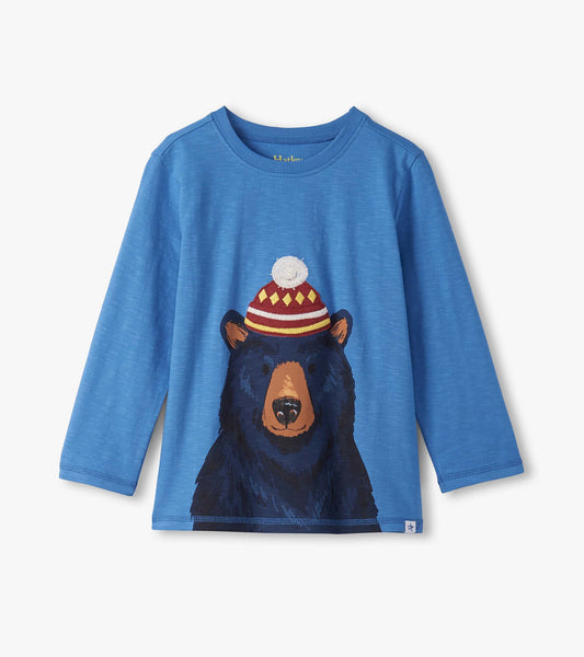 Blue long sleeve tee featuring a graphic of a bear wearing a red and yellow striped hat with a pom-pom.