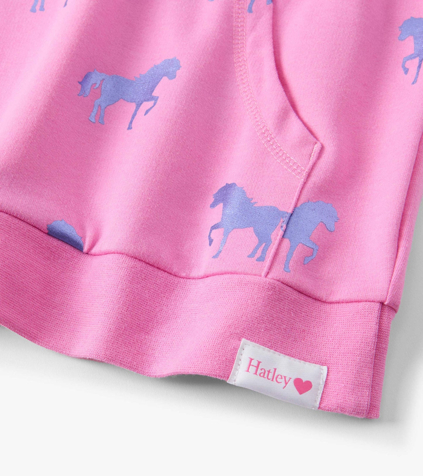 Pink sweater featuring a pattern of blue horses, made from soft material with a rounded neckline and ribbed hem.