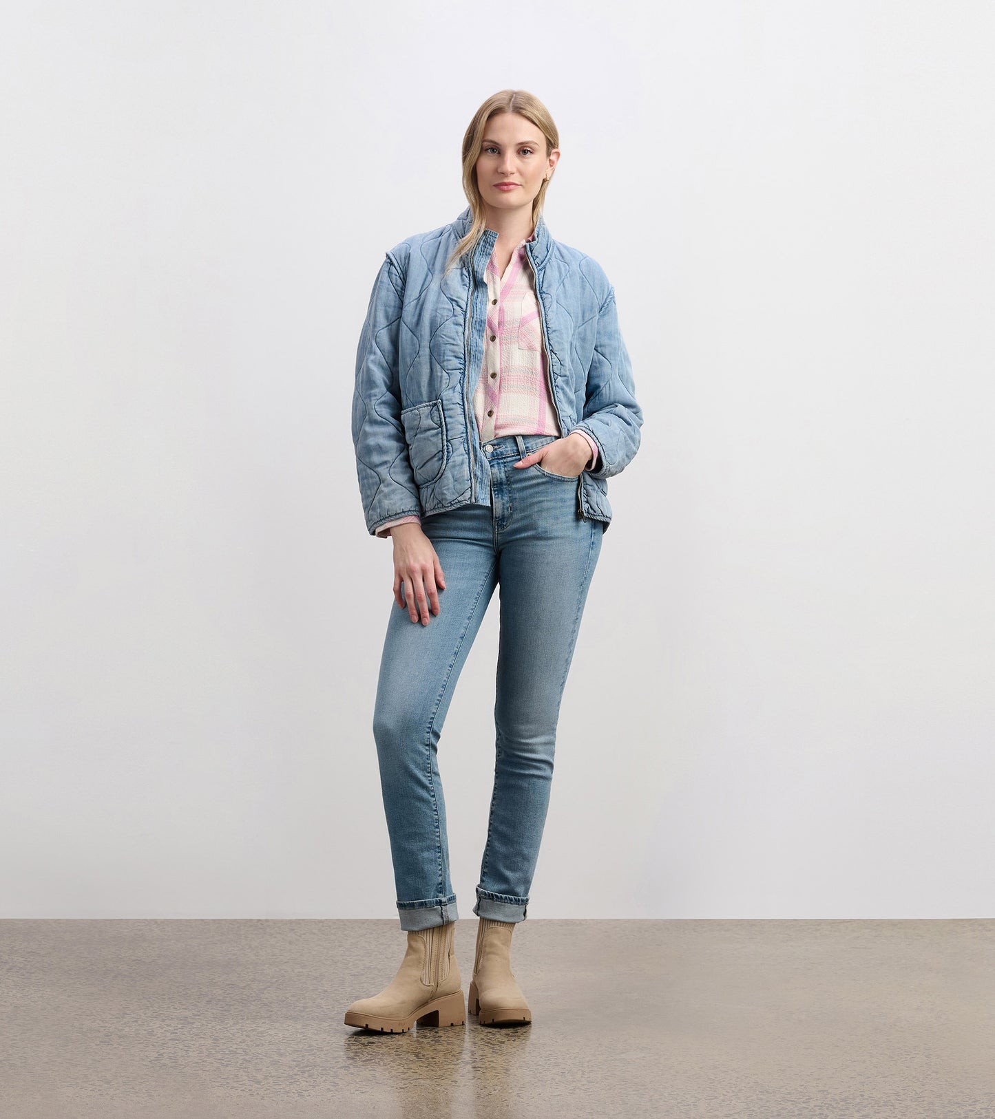 Front view of washed blue quilted jacket with patch pockets and mock neck, styled with jeans