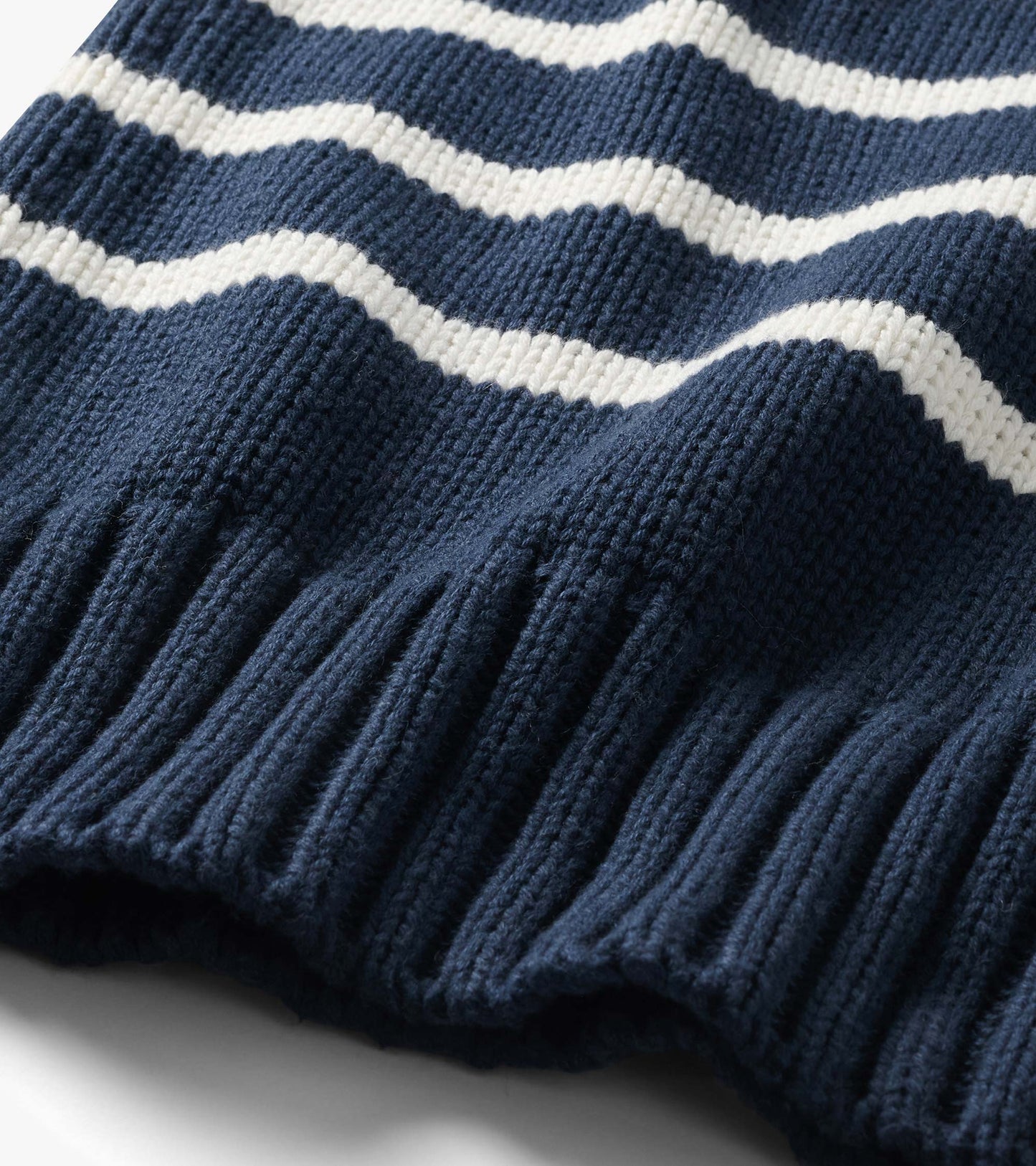Close-up of navy sweater with cream stripes and wide ribbed hem