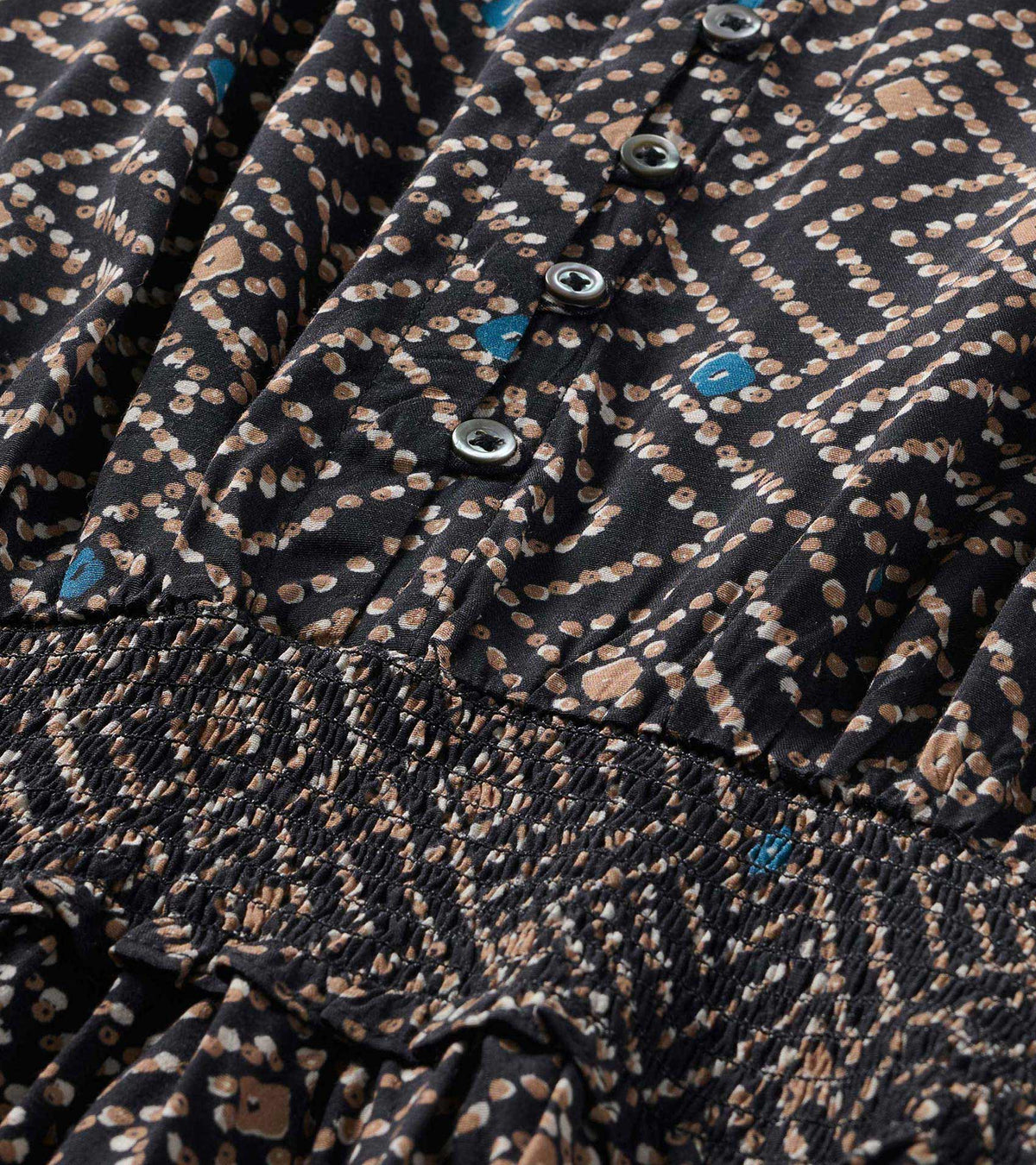 Close-up of the broken ikat print dress with front buttons and smocked waist detail