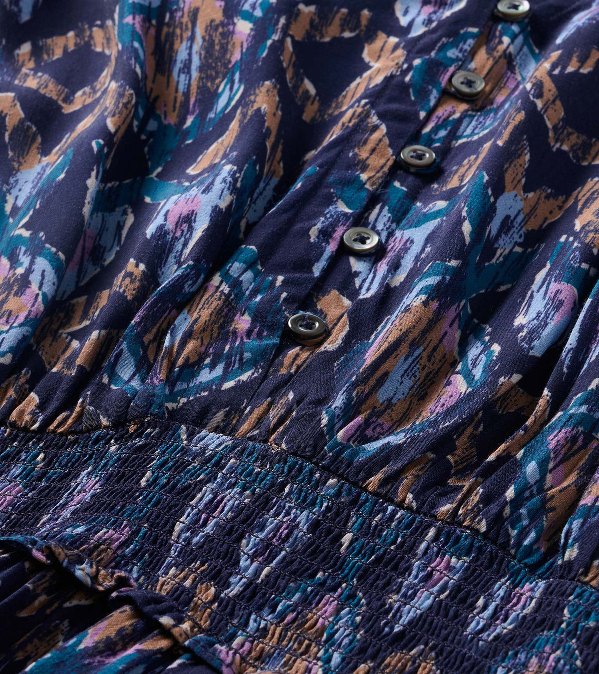 Close-up of the dress's textured ikat print, front buttons, and smocked waist detail