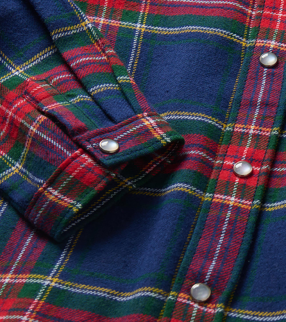 Close-up of navy, red and green plaid shirt showing snap buttons and cuff detail