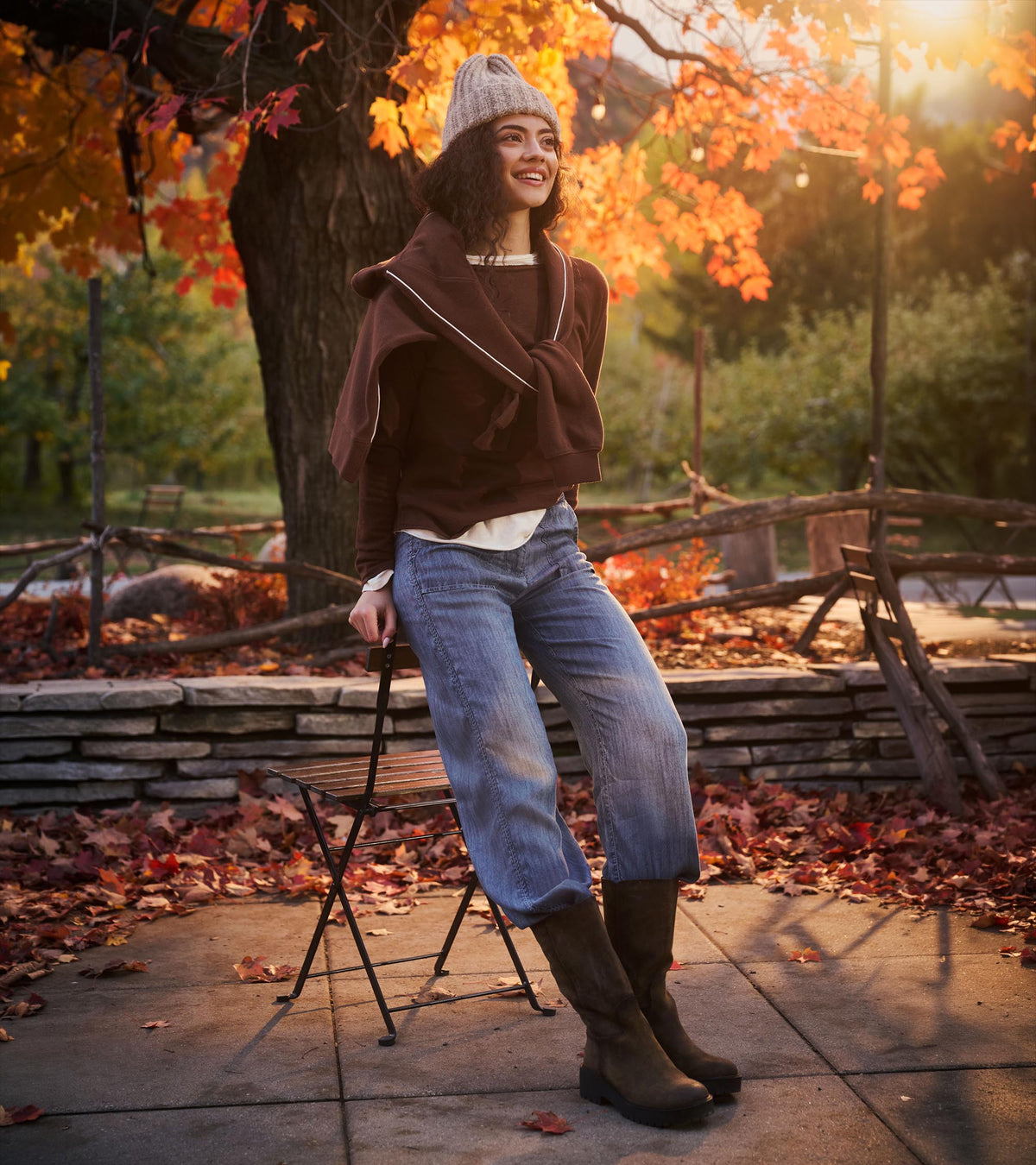 Blue acid rinse wide leg pants styled outdoors with a brown top, knit hat, and ankle boots