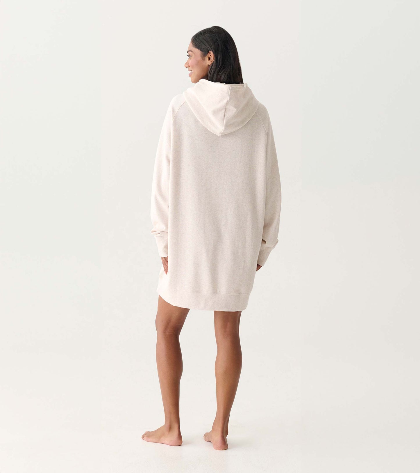 Oversized cream hooded sweatshirt dress shown from the back on a model, with long sleeves and a relaxed fit