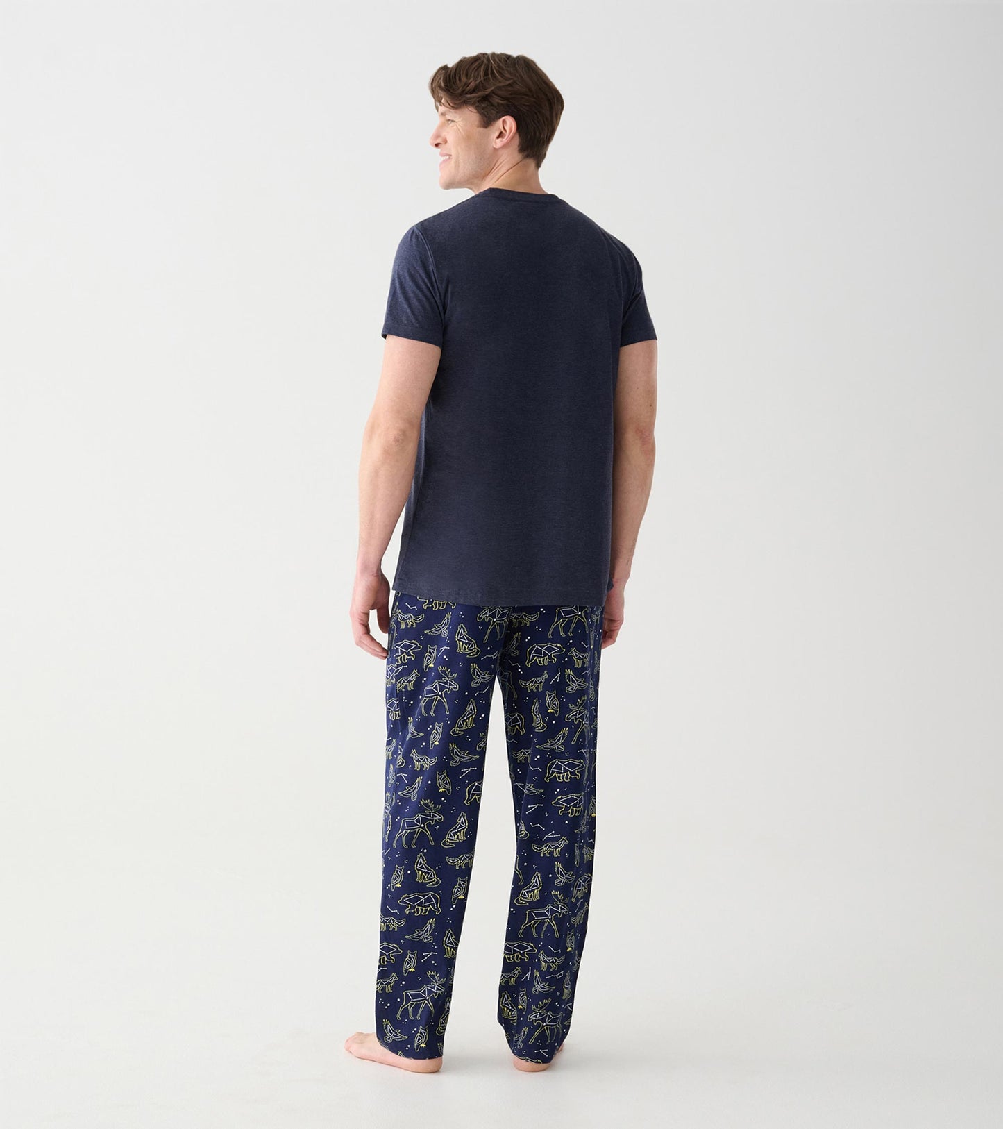 Rear view of navy animal constellation pajama pants worn with a plain dark short sleeve tee