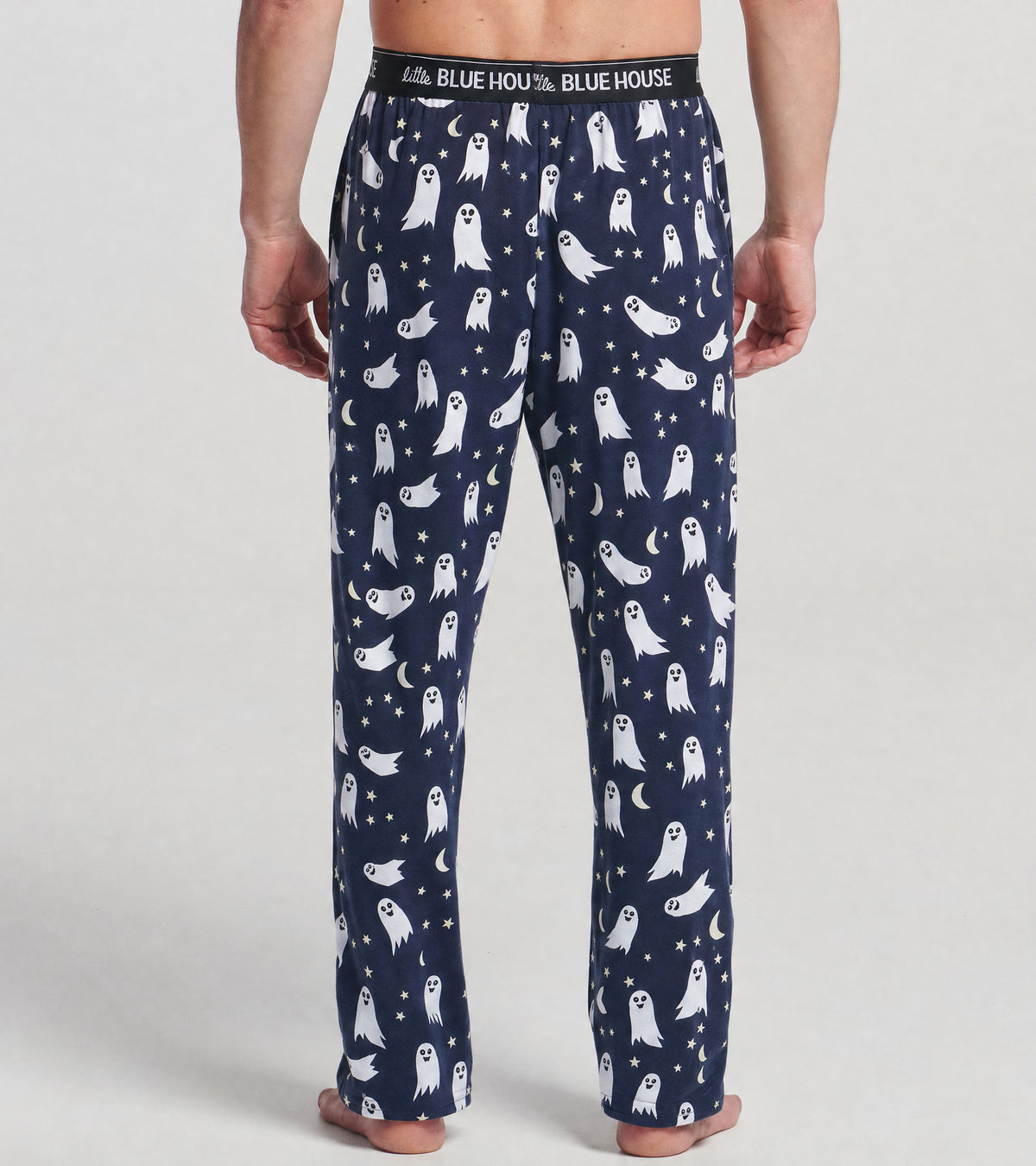Back view of navy pajama pants with white ghosts, stars and crescent moons, worn by model