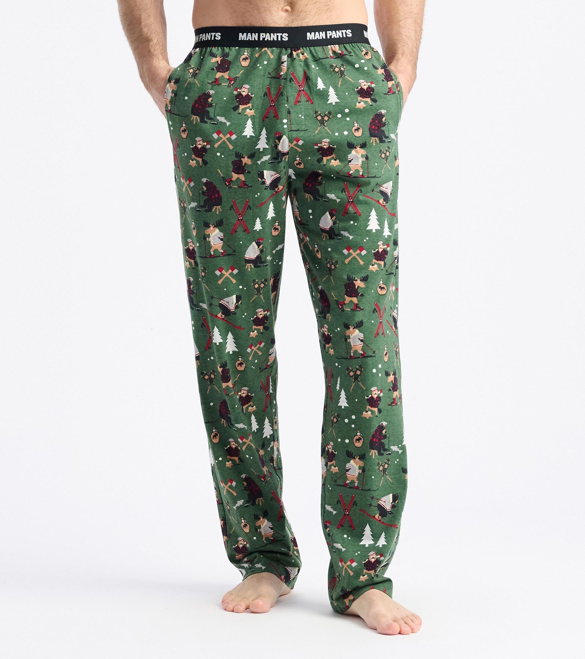 Green pajama pants featuring a winter-themed pattern with trees, bears, and outdoor activities. Elastic waistband visible.