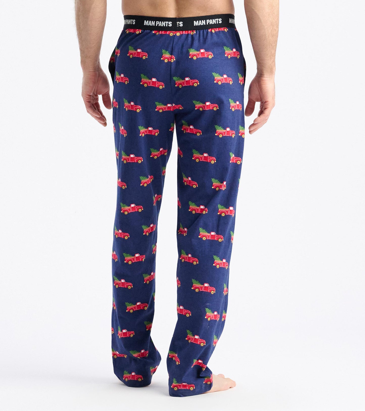 Navy pants featuring a playful pattern of red trucks hauling Christmas trees, with an elastic waistband.