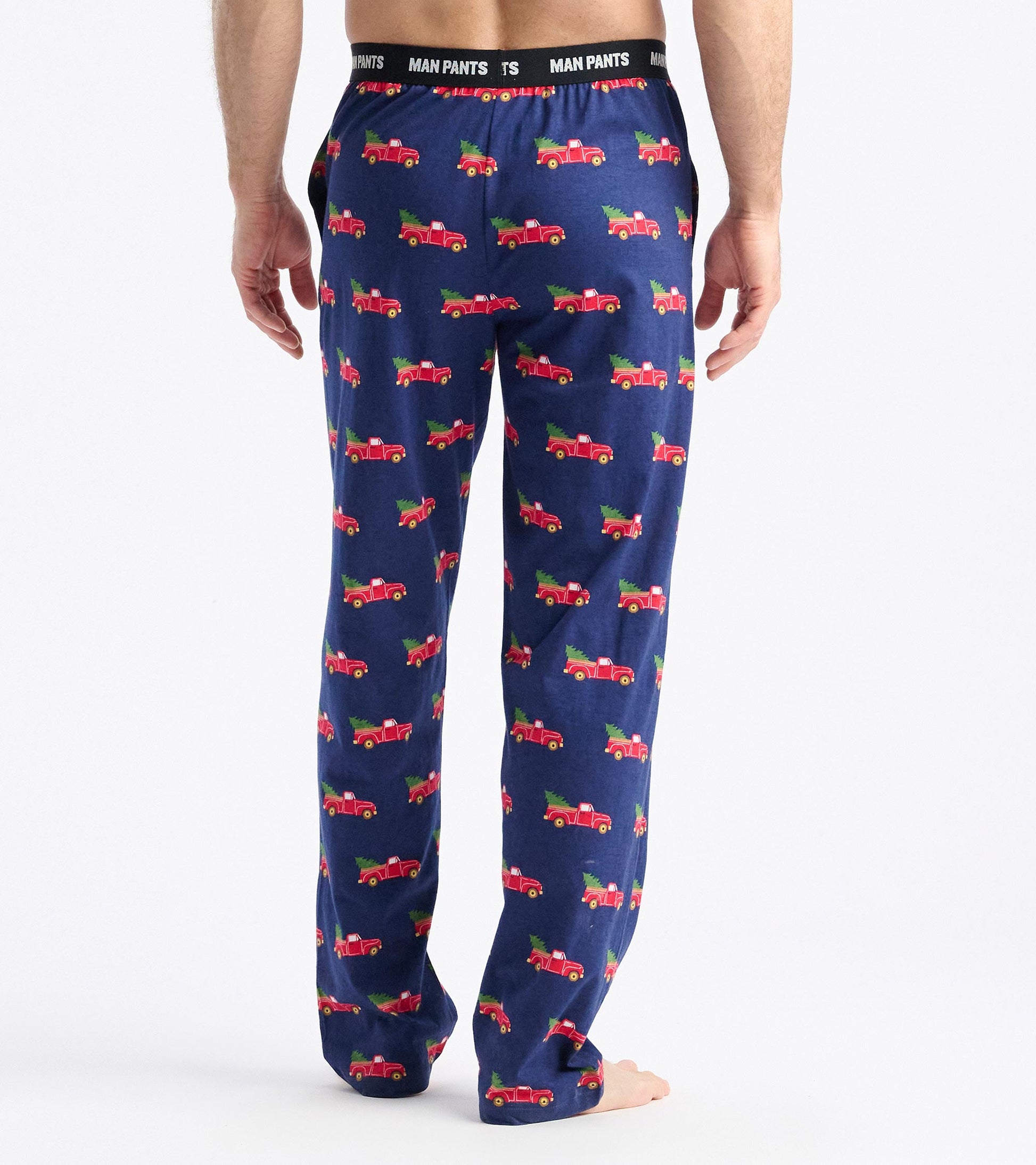 Navy pants featuring a playful pattern of red trucks hauling Christmas trees, with an elastic waistband.