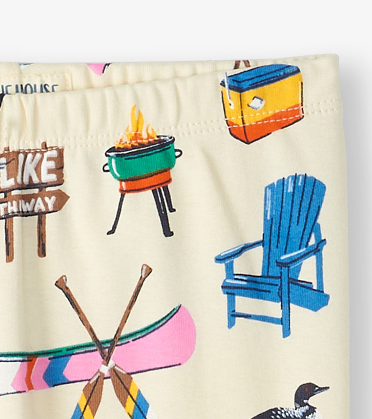 Kids pajama set featuring a light background with colorful camping-themed prints, including canoes, chairs, and a campfire.