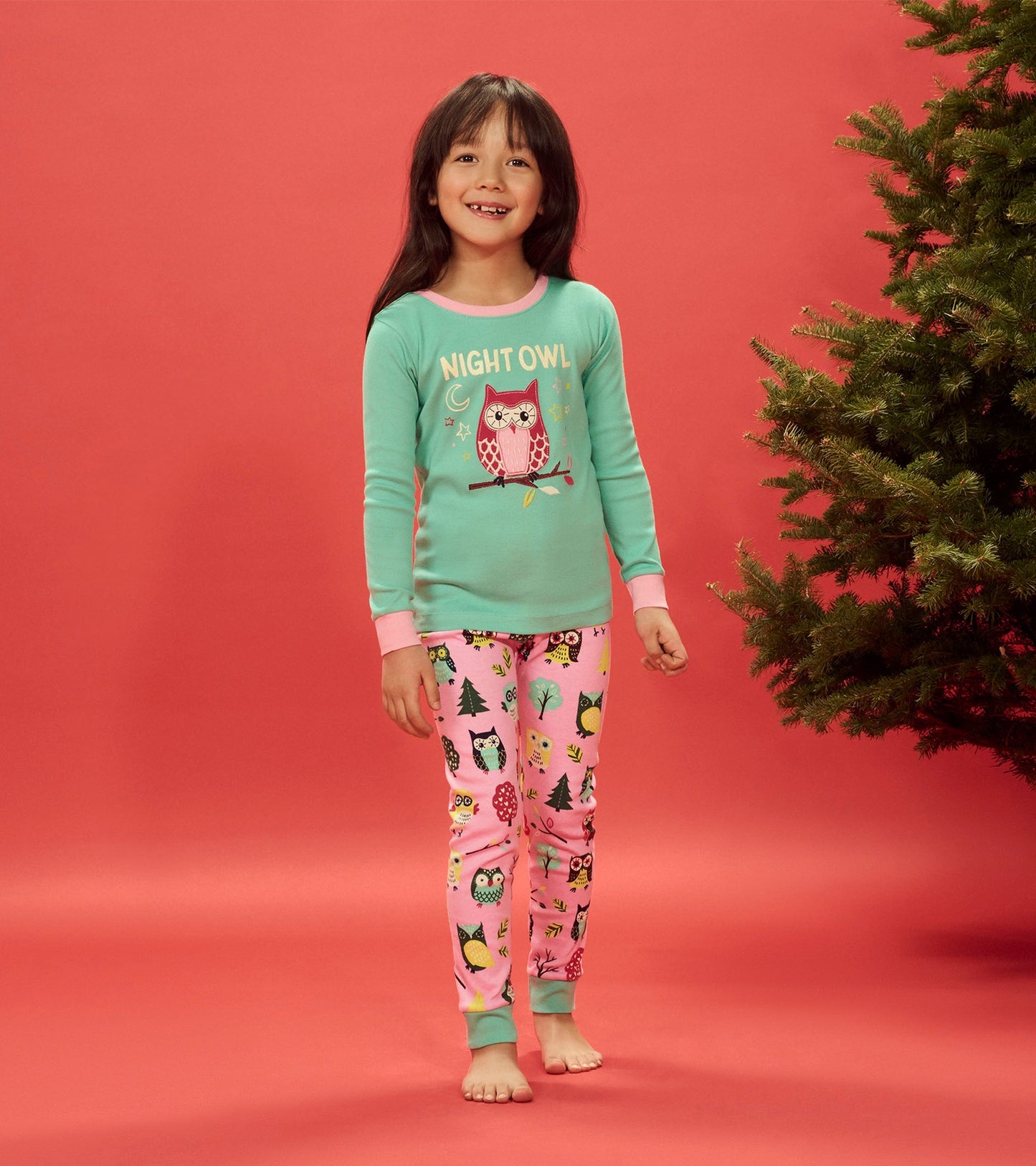 Turquoise long-sleeve pajama top with owl graphic, paired with pink pants featuring colorful owl and tree patterns.