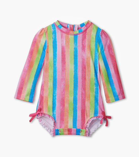 Long-sleeve rashguard swimsuit featuring vibrant rainbow stripes in pink, green, blue, and yellow with snap closures at the…