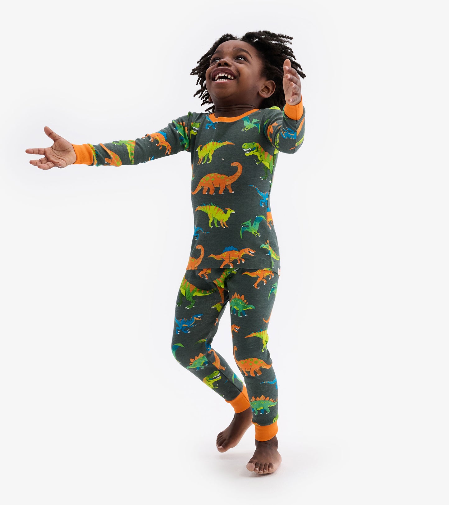 Colourful dinosaur patterns on a dark grey pajama set with orange cuffs, designed for kids.