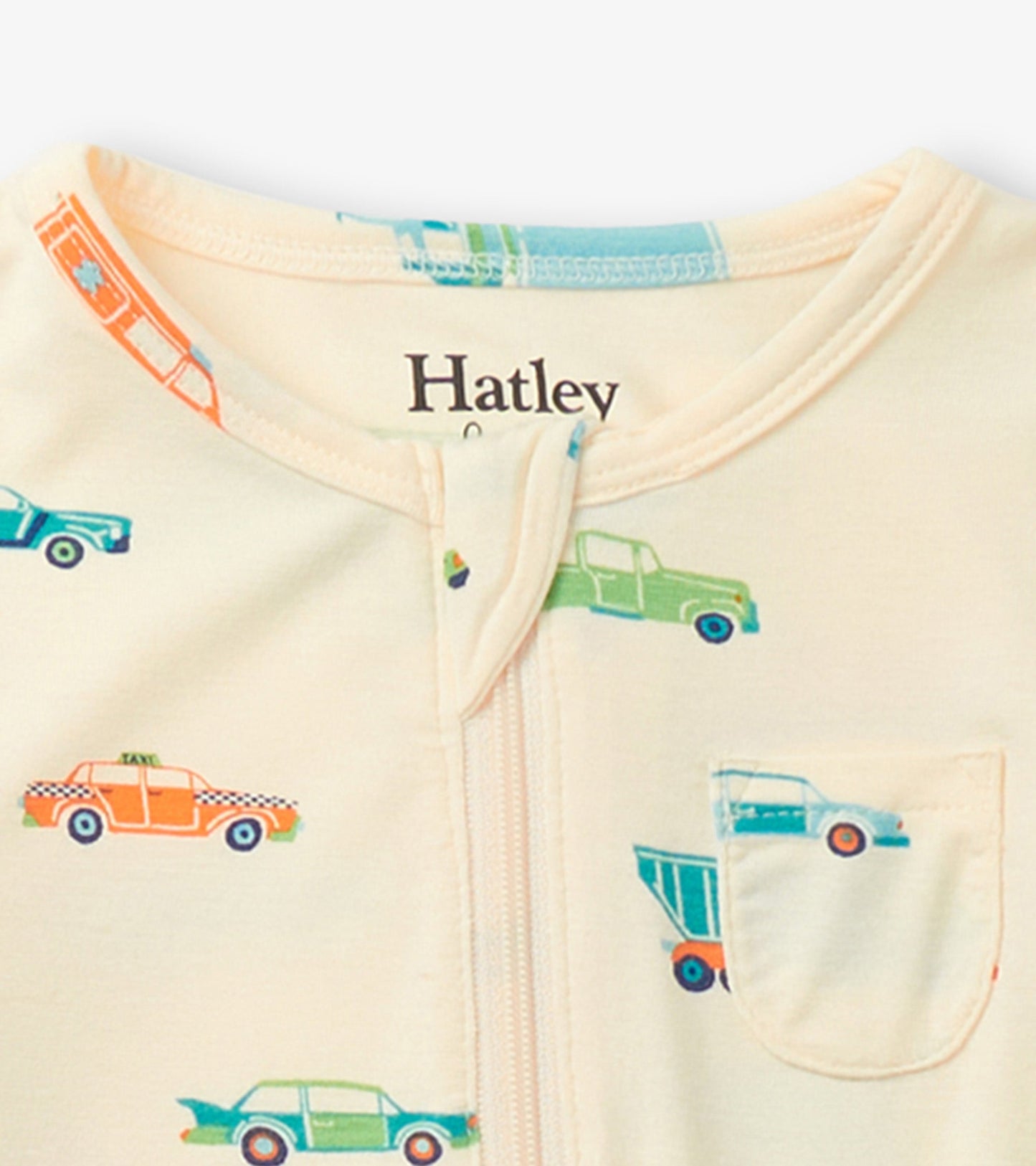Cream footed sleeper featuring colorful car prints, with a zip closure and a small pocket on the front.