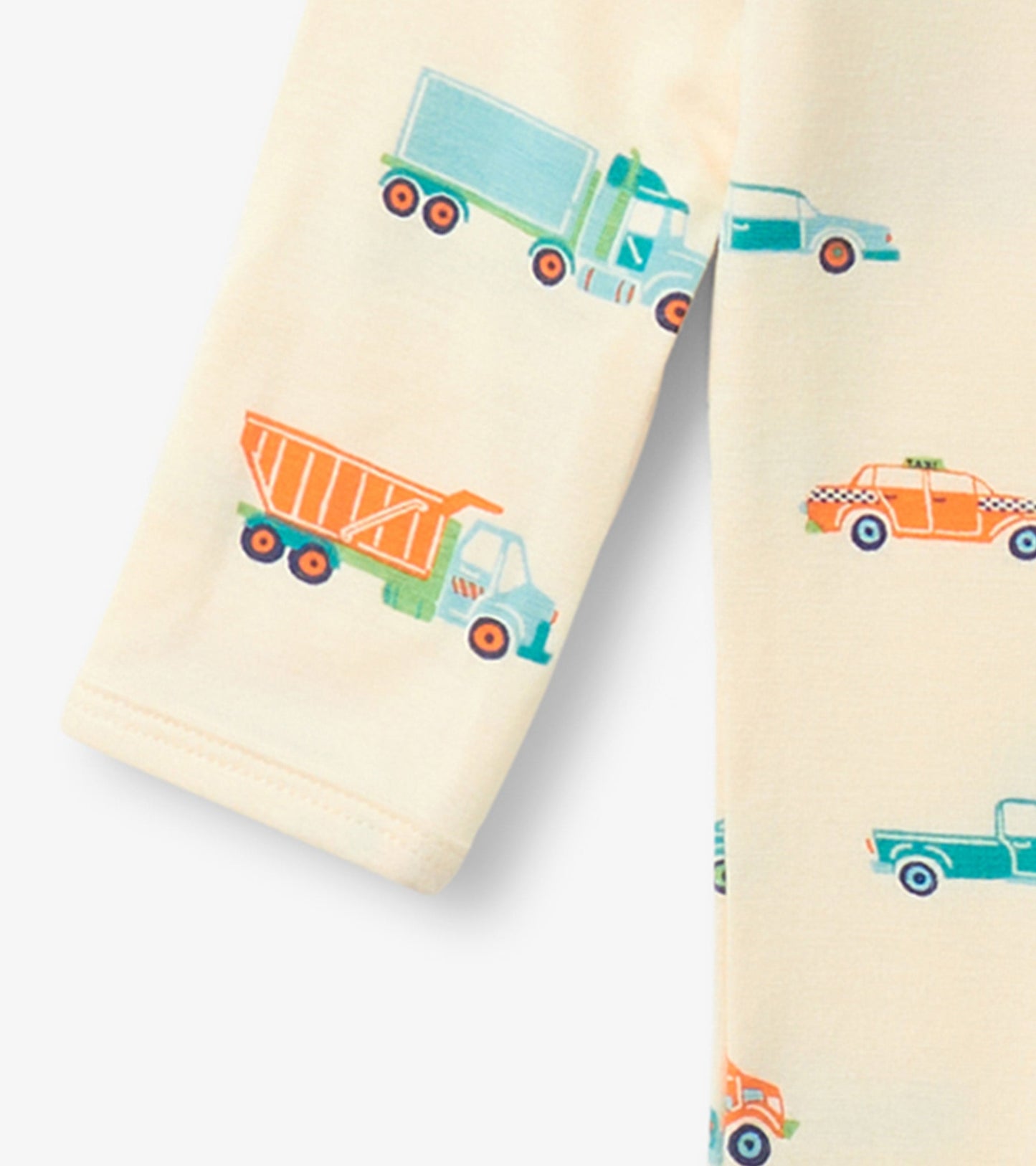 Cream footed sleeper featuring colorful truck and car prints, ideal for baby boys. Soft fabric with long sleeves.