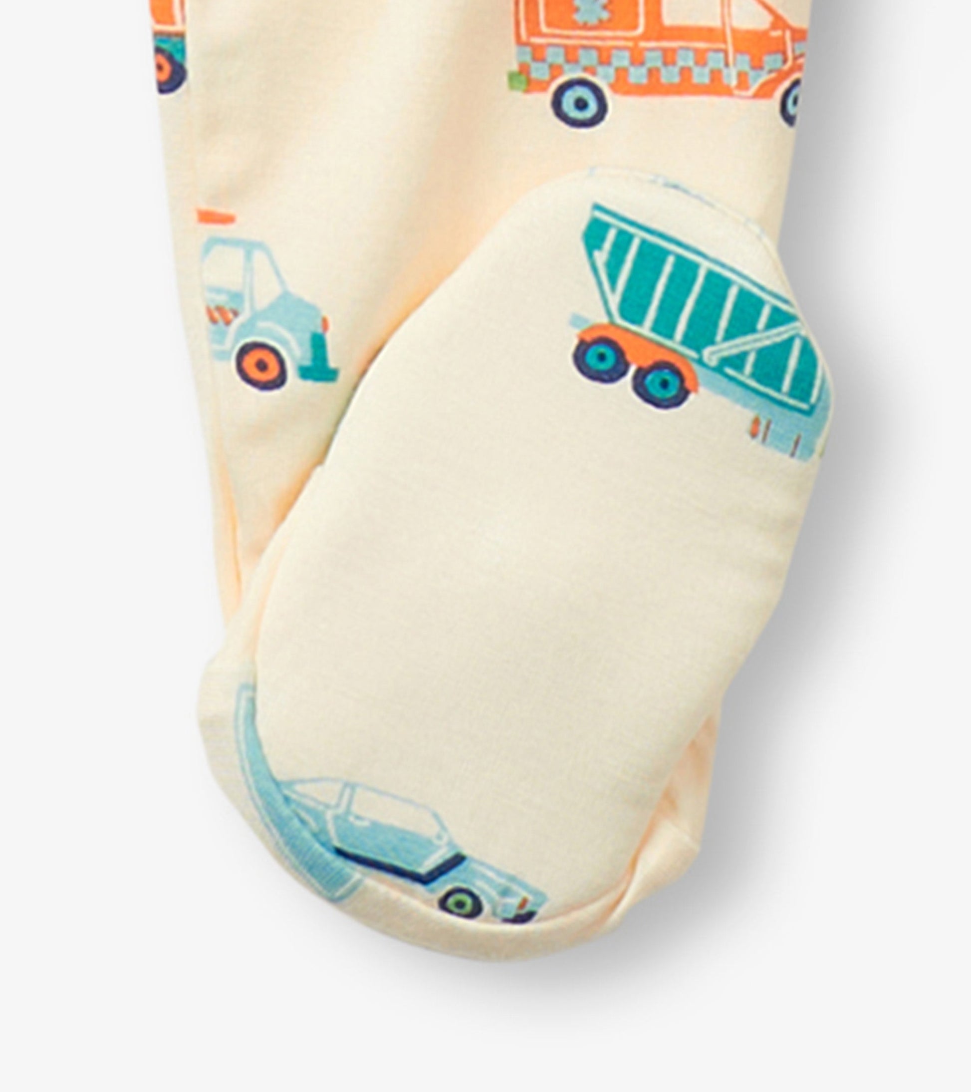 Cream footed sleeper featuring colorful car and truck prints, designed for baby boys, with enclosed feet for warmth.