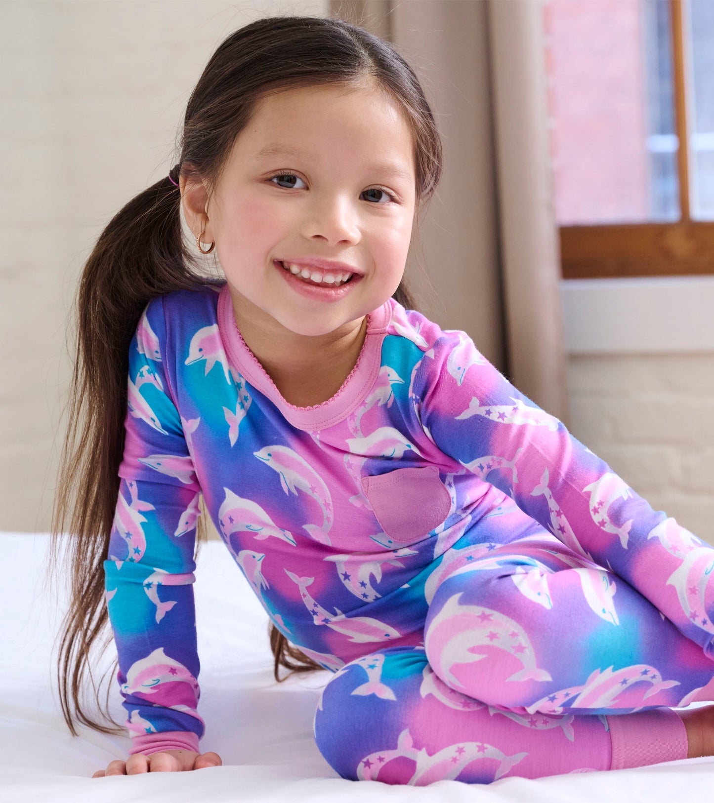 Colorful long-sleeve pajama set featuring dolphins on a pink and blue gradient background, perfect for girls.