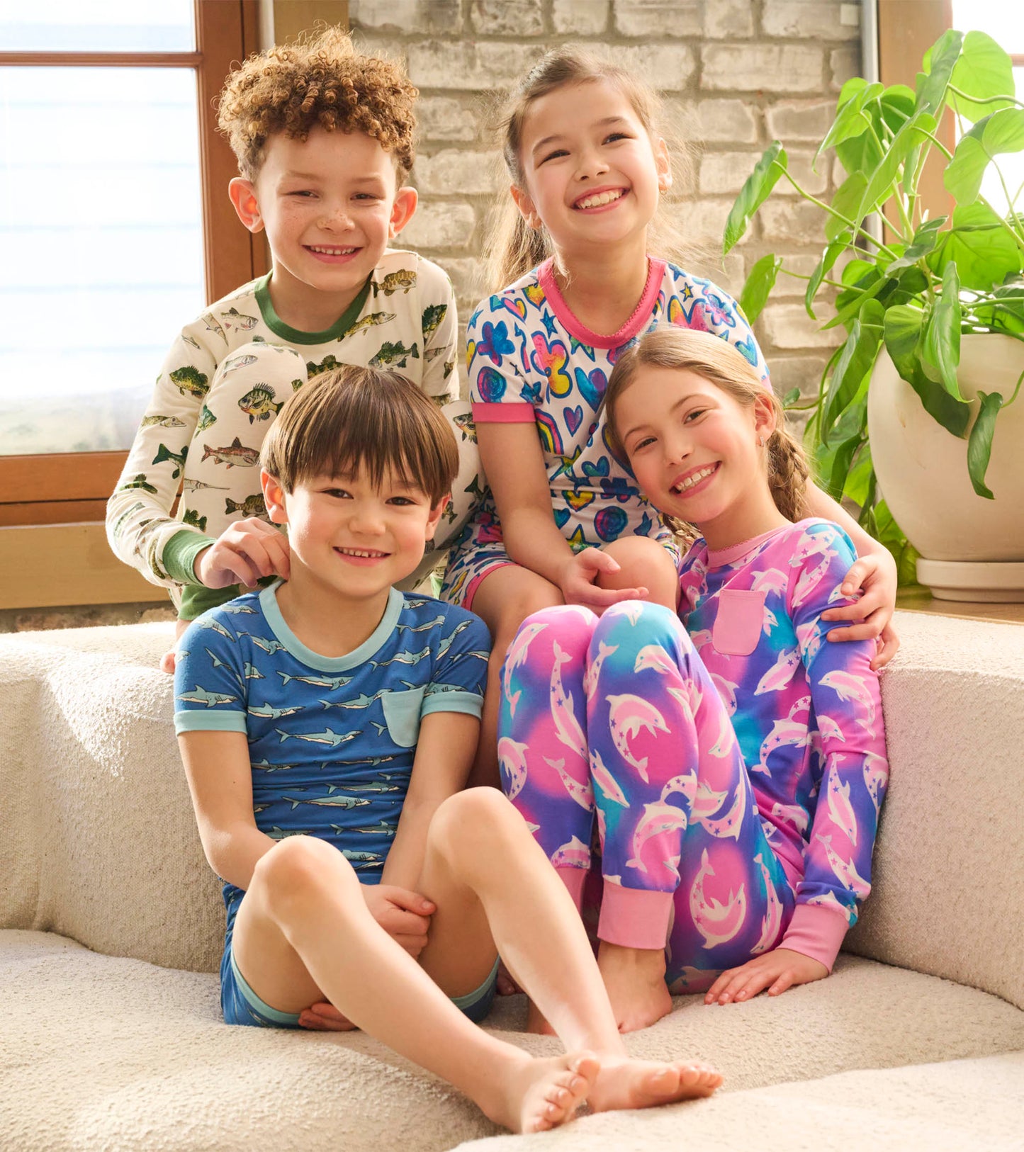 Colorful pajama set featuring dolphin patterns, worn by four children sitting together on a cozy couch.