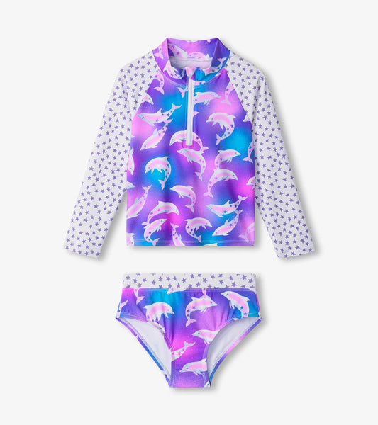 Purple and pink dolphin-patterned rashguard set with long sleeves and matching bikini bottom, featuring star accents.