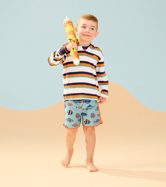 Striped terry pullover hoodie in white, navy, and orange, worn by a boy with aqua fish-patterned shorts.