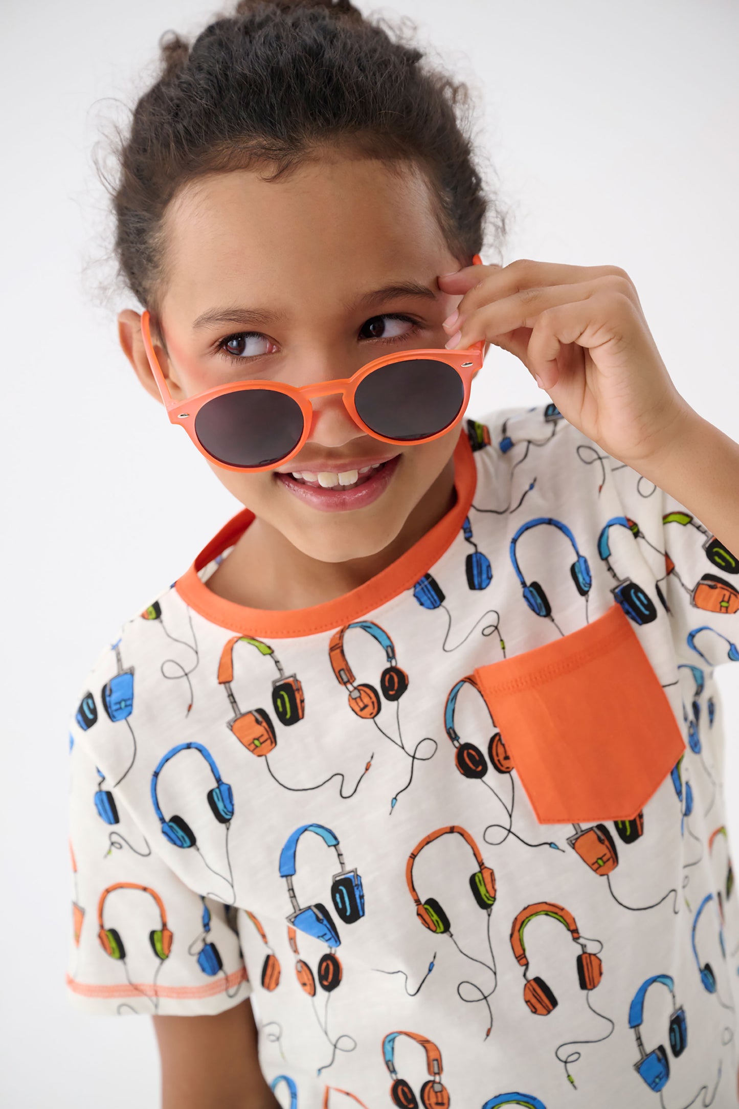 Short-sleeve t-shirt featuring colorful headphone patterns and an orange pocket, perfect for casual wear.