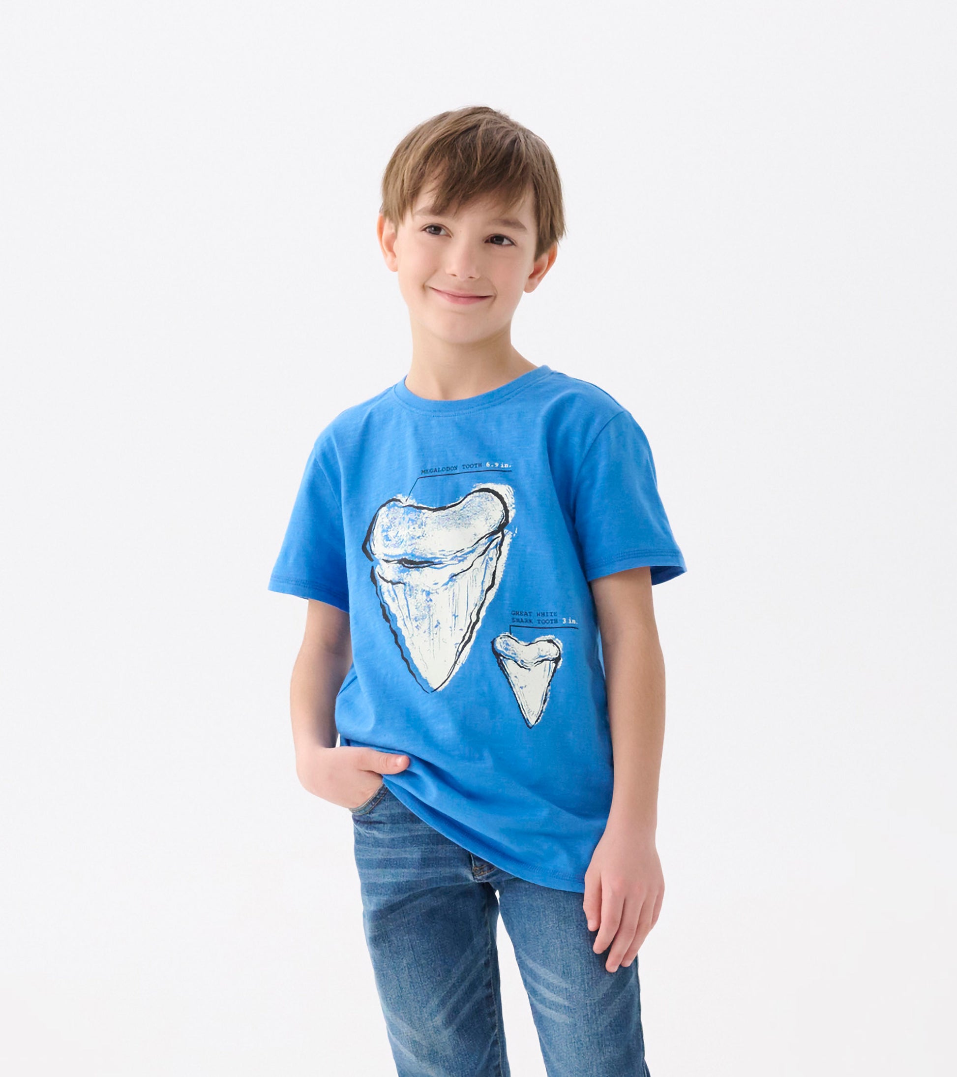 Blue graphic tee featuring shark tooth illustrations, short sleeves, and a relaxed fit, worn by a smiling boy.