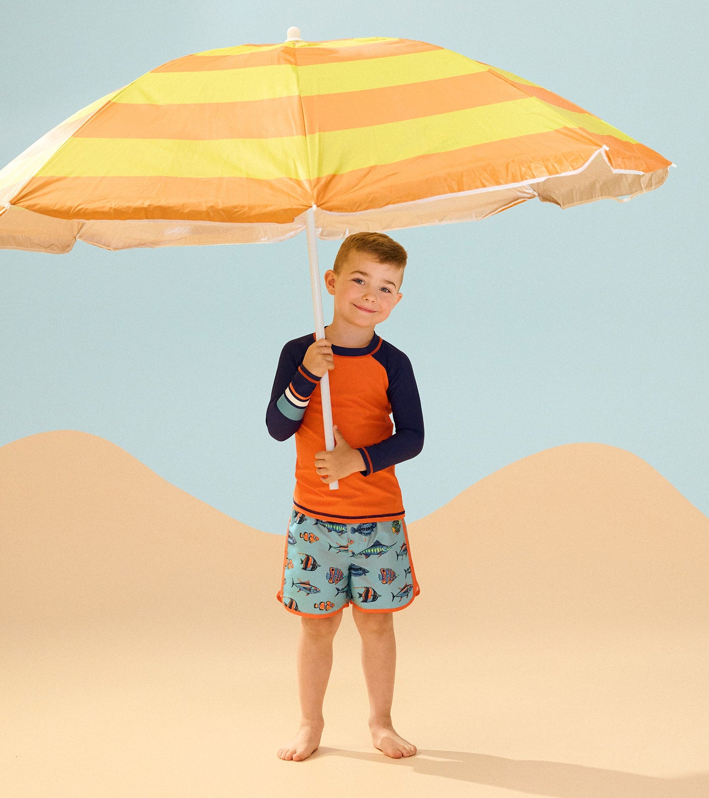 Boys' long sleeve rashguard in bright orange with navy sleeves, perfect for beachwear and sun protection.
