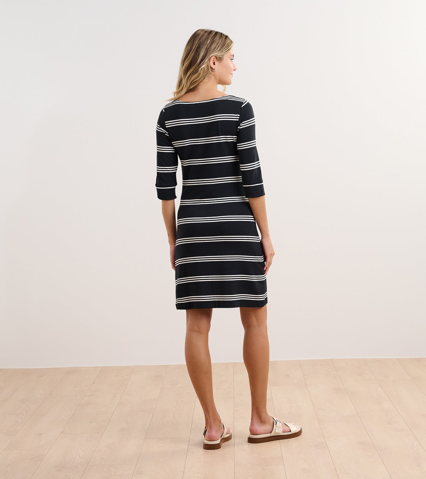Black and white striped dress with three-quarter sleeves, shown from the back, paired with casual sandals.