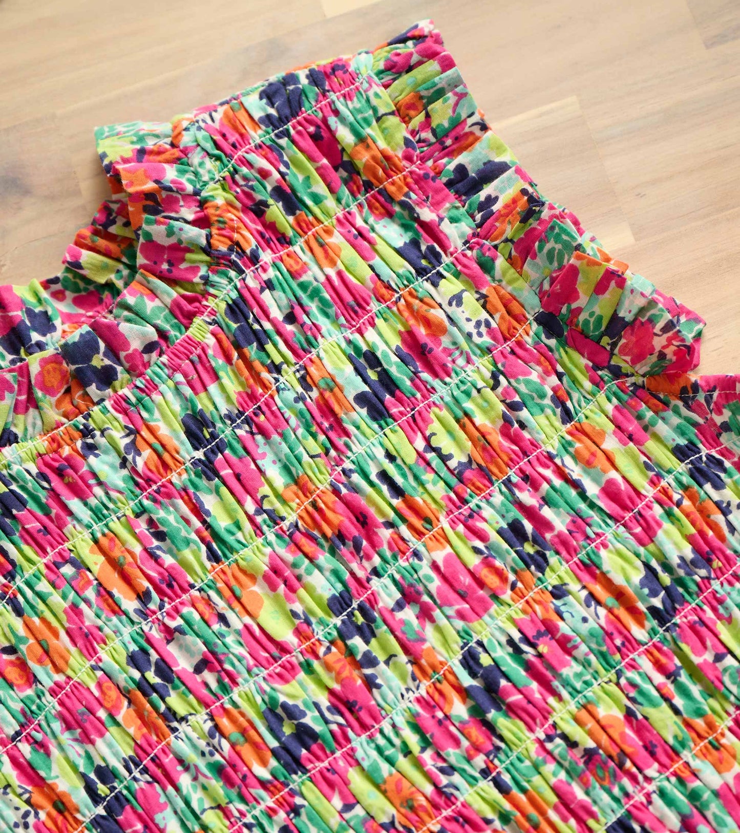 Colorful smocked maxi dress featuring a vibrant floral pattern in pink, green, and orange hues.