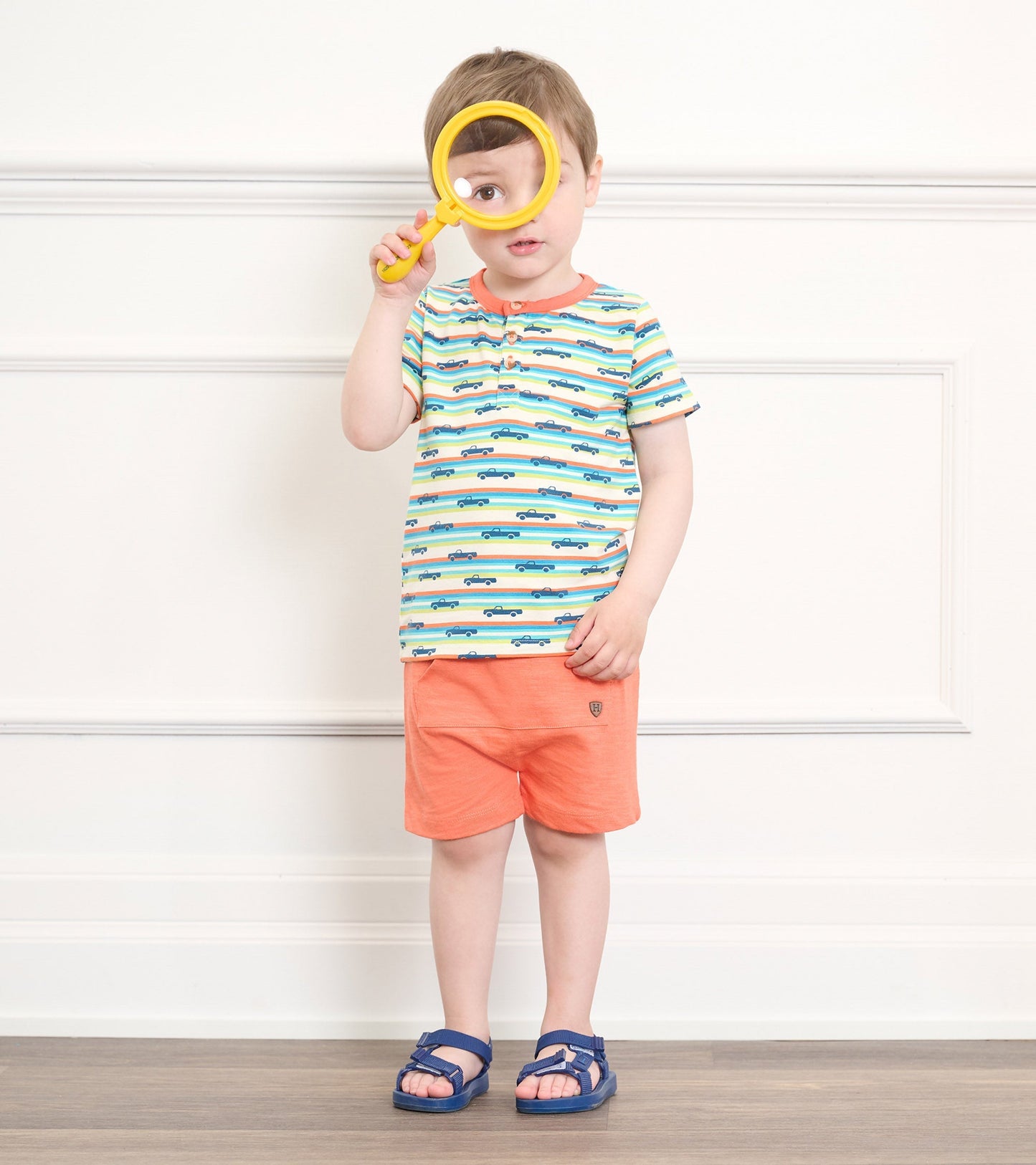 Coral kangaroo shorts with a relaxed fit, paired with a striped shirt featuring blue car patterns.
