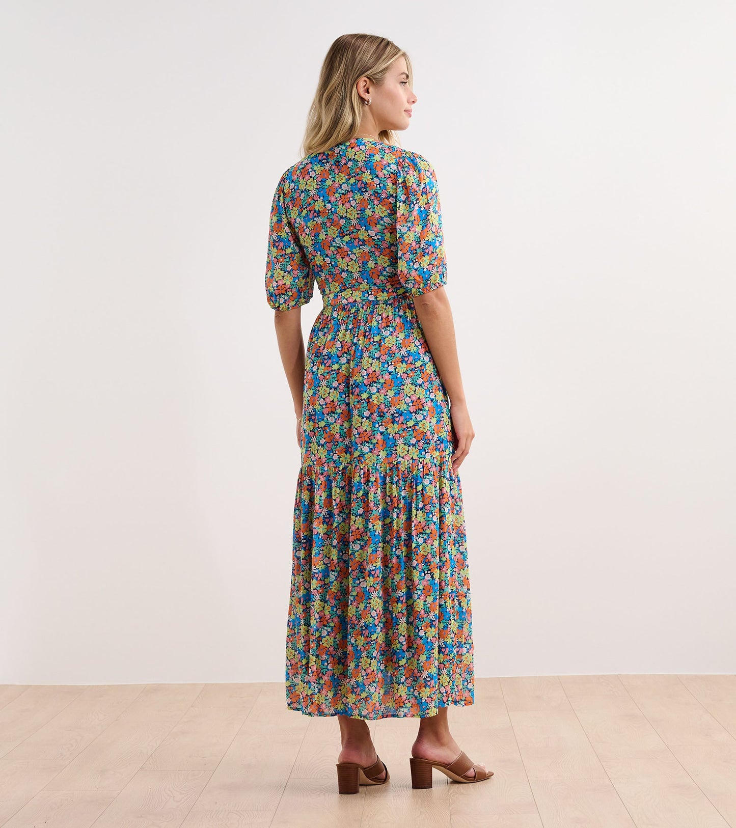 Maxi dress with a vibrant floral pattern in blue, pink, and green, featuring short puff sleeves and a tiered skirt.