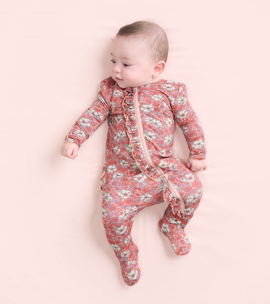 Footed sleeper for baby girls featuring a groovy floral pattern in pink and blue, with a front zipper and ruffle details.