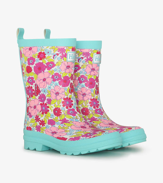 Colorful matte rain boots featuring a floral pattern in pink, yellow, and blue with a textured turquoise sole.