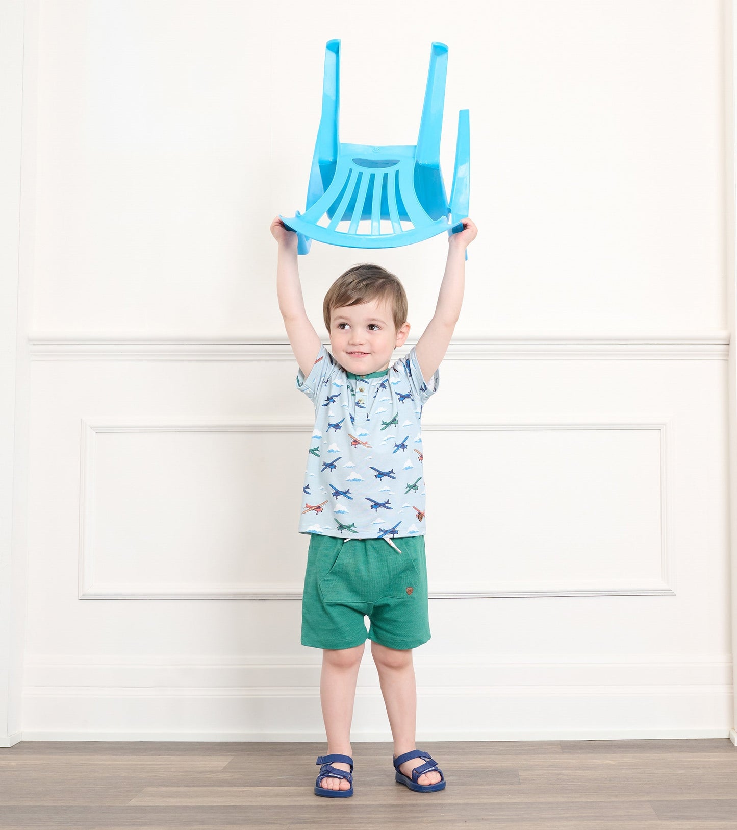 Emerald green kangaroo shorts on a toddler, paired with a light blue shirt and blue sandals, in a bright indoor setting.