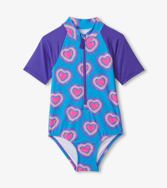 Blue one-piece rashguard with purple sleeves, featuring a heart pattern in pink and purple, ideal for swimming.