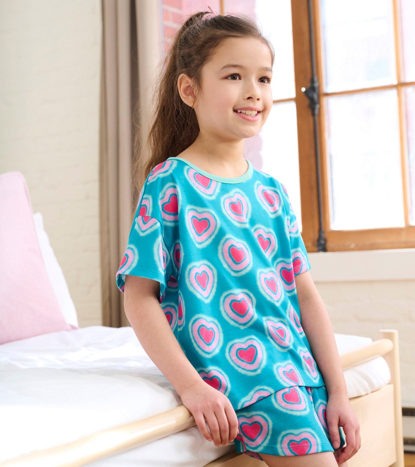 Turquoise pajama set featuring a heart pattern, includes a short-sleeve tee and matching shorts, ideal for girls.